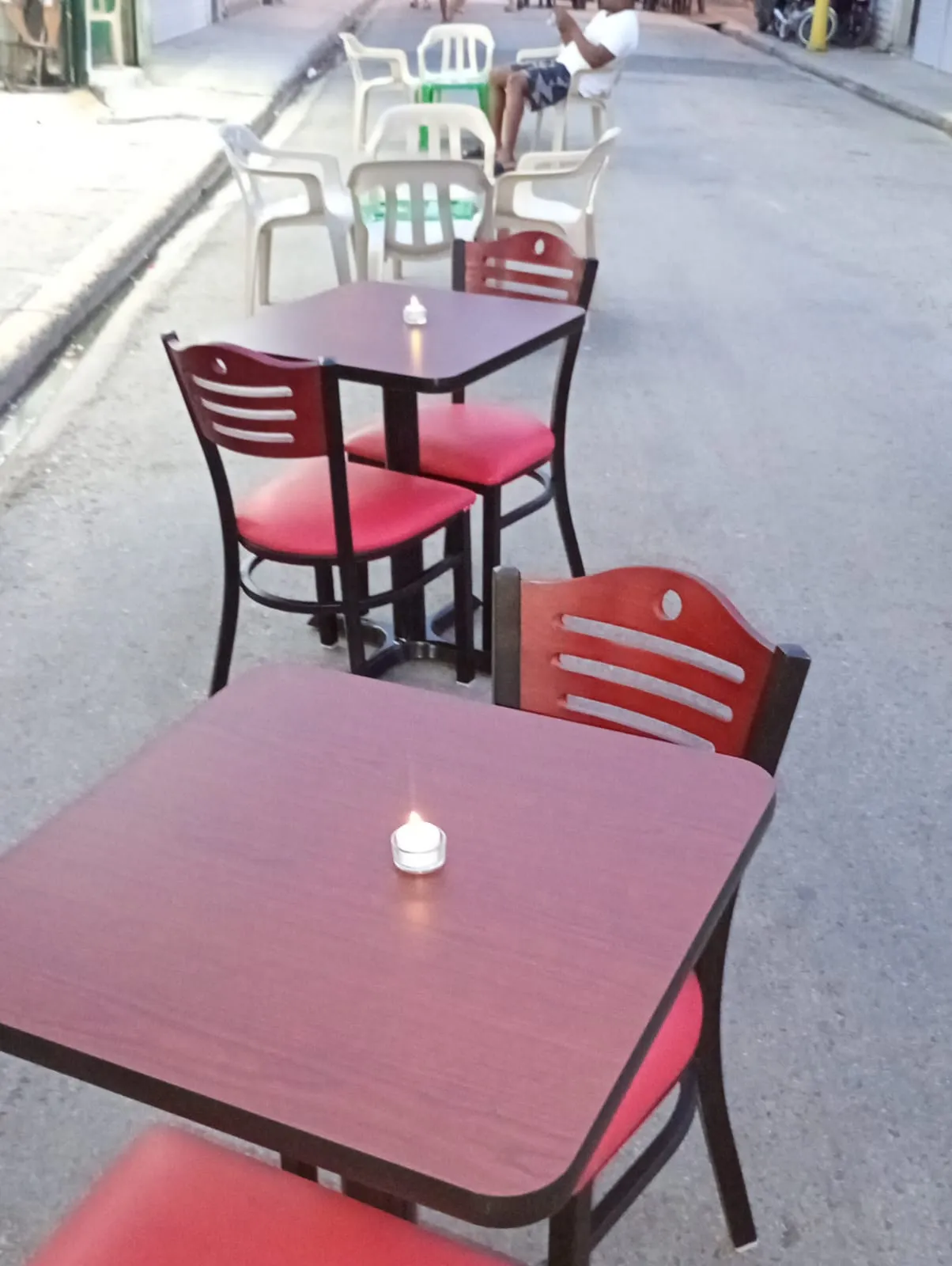 Tables with red chairs and candles out on the street