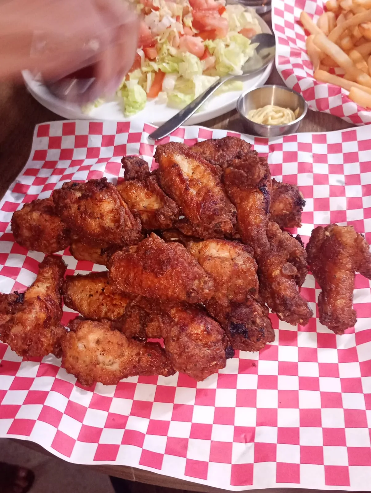 A basket of chicken wings on red and white checked paper